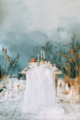 Autumn decor with fabric and dried flowers. Wedding in the style of fine art. Wedding table decor with candles.