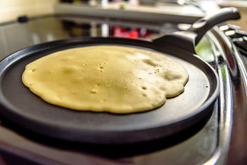 pancake frying pan with crepe pancake cooking on cooker in kitchen