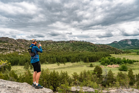 A male runner shoots a photo on a smartphone of an ancient temple in the mountains. Buddhist temple in mountains Kent. The ancient settlement of the Dzhungars. Kazakhstan