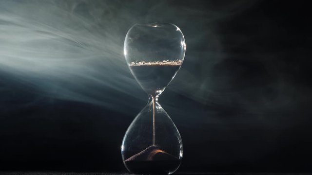 Hourglass on a black background where the mist swirl