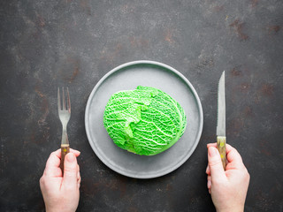 H&auml;nde mit rustikalen Besteck und einem frischen Kohl auf einem grauen Teller, Flat lay, Di&auml;t, gesunde Ern&auml;hrung