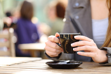 Woman holding coffee cup on her hands on a terrace