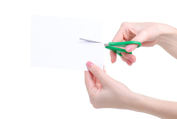 Hand holding green office stationery scissors cutting white paper on white background isolation