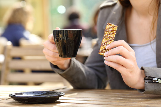Woman holding a snack bar and coffee cup on a terrace