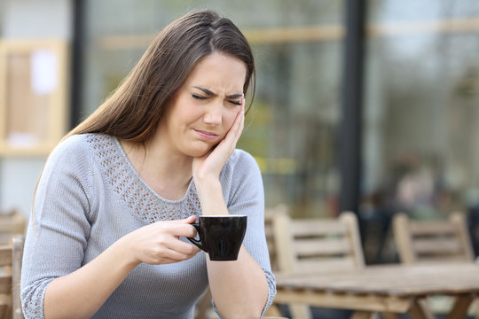 Woman Suffering From Tooth Ache Holding Coffee Mug On A Terrace