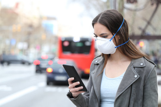 Woman with mask using phone with city traffic background