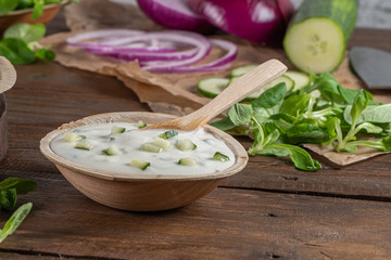 View of wooden cutting board on old wooden table top with tablecloth and yogurt sauce dip in a bowl