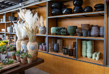 A variety of beautiful flower pots and vases on the shelves of the greek flower boutique in spring.