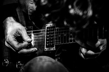 Hands playing on a guitar in a concert on a stage in a club