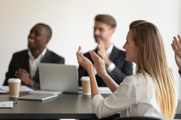 Side view head shot smiling young woman applauding to speaker, mixed race millennial colleagues team feeling joyful, celebrating great work results, company success at business meeting at office.