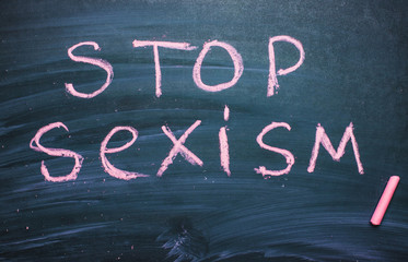 Stop sexism is written on a chalkboard chalk