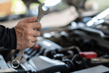 Professional mechanic man holding spanner tool for repair and maintenance car in garage