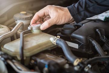 Professional mechanic man holding radiator cap for checking and preventive maintenance service car in garage