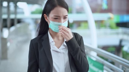 Asian business woman wearing medical mask protection walking in the business district and feeling smell of air polution, virus, covid-19 coronavirus and flu concept. - Powered by Adobe
