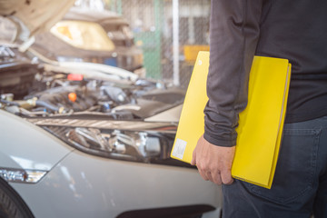Yellow folder service report working in hand of mechanic man, car service maintenance and repair garage