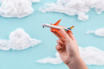 Child playing with toy airplane on handmade blue sky