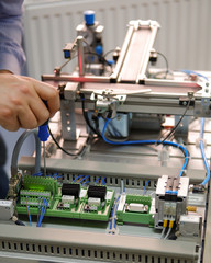 Closeup of male technician repairing automation system's electronic card by screwdriver.	