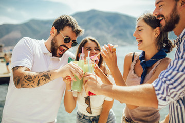 Friends at the beach drinking cocktails having fun on summer vacation