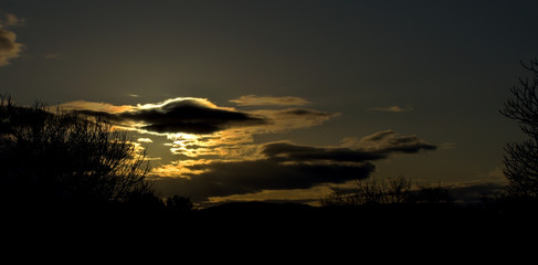 Puesta de Sol en tonos grises, azules y violetas con el contraste de la luz en tonos amarillos y naranjas tenues