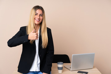 Young business woman in a office giving a thumbs up gesture