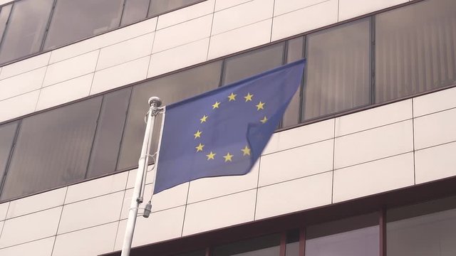 4k video EU flag fluttering on strong wind against high modern business center
