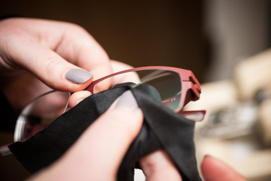 Eine Frau reinigt eine Brille, Brillenglas