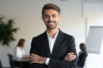 Head shot portrait of young happy confident businessman, client or investor. Smiling office worker, company employee, executive manager, salesman, male team leader, lawyer standing with folded hands.