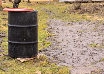 black barrel in the garden in early spring. mud on the path