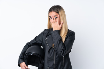 Young Uruguayan woman with a motorcycle helmet over isolated white background covering eyes and looking through fingers