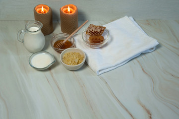 Natural home skin care. The pleasure of taking a bath. Sweet Golden honey, milk,sea salt, burning wax candles and clean towels on a background of pastel green marble. Free space.