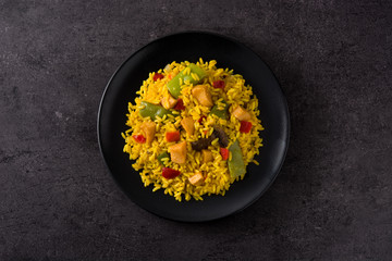 Fried rice with chicken and vegetables on black plate