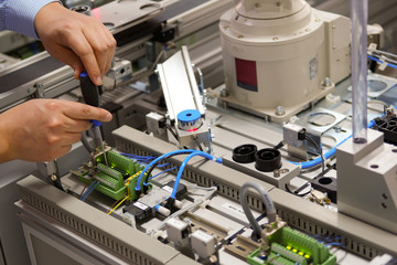 Closeup of male technician repairing automation system's electronic card by screwdriver.	