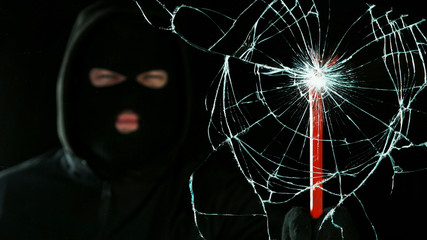 Detail of shattered glass, burglar on background