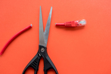 with a pair of scissors cut the connector at the red cable red background