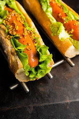 Tasty fresh hot dogs with grilled sausage, french mystard and fresh salad leaves on the rustic...