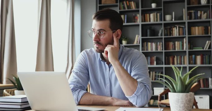 Concentrated serious businessman thinking of problem solution working on laptop. Thoughtful male programmer market analyst or software developer considering risks using computer sitting at workplace.