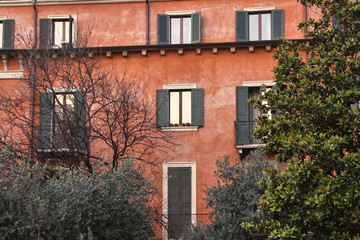 Fototapeta na wymiar Wall of a house with red old stucco and gray window shutters