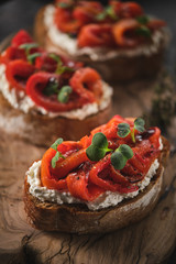 Sandwich with soft cheese and baked red bell pepper on a wooden board.