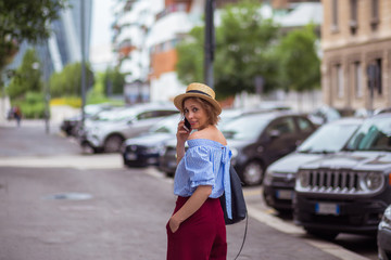 Fototapeta premium The girl in the hat walks around the city and speaks on the phone