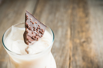 Creamy cocktail with ice and slice of chocolate. Selective focus. Shallow depth of field.