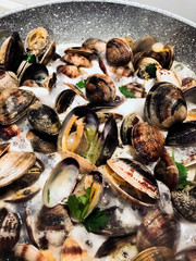 cooking clams in a stone pan using parsley and white wine.