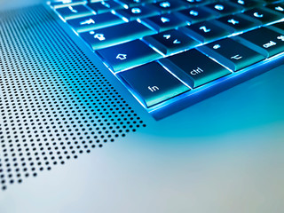 close up view of a metal keyboard of a computer with the keys backlit with a blue light