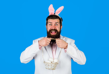 Easter tradition and symbol. Bearded man in bunny ears hold basket with eggs. Happy Easter....
