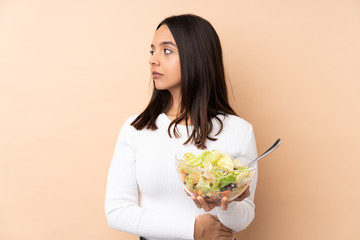 Young brunette girl holding a salad over isolated background portrait