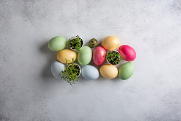 Heap of dyed multi-colored eggs and green sprouts in egg shell  on concrete background. Top view,...