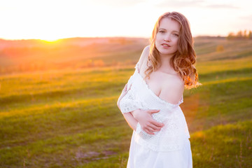 Fototapeta na wymiar Beautiful smiling woman in a field at sunset