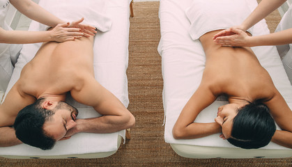 Beautiful mixed race couple getting massage at beauty spa.
