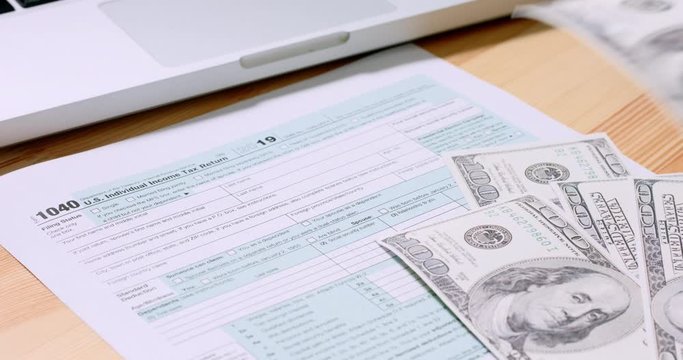 U.S. 1040 tax return form with 100 usd dollar bills. Overhead, 4k
