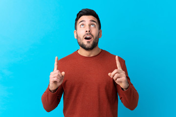 Young handsome man with beard over isolated blue background pointing with the index finger a great idea