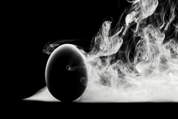 concept. The contour of the eggs on a black background and white steam or smoke.